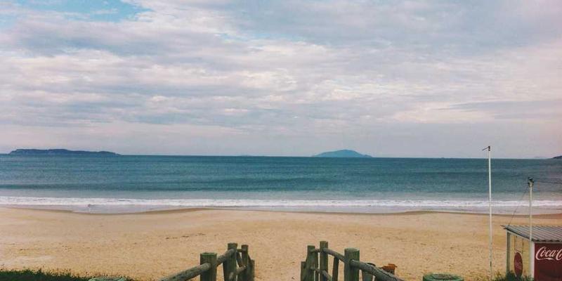 一粒金黄色的沙粒在阳光下的特写，背景为无垠的沙滩
